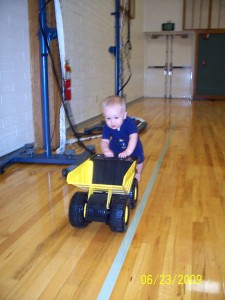 Pushing a dump truck around the gym at playgroup.