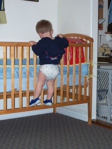 Aiden tries to reach something in Lucas' crib.